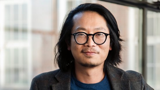 Dr. Sung-Joon Park: ein Forscher der schulterlanges Haar, eine runde schwarze Brille, ein dunkles Sakko über einem dunkelblauen Oberteil trägt.