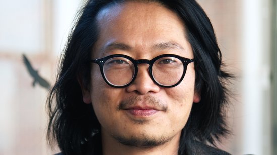 Dr. Sung-Joon Park: ein Forscher der schulterlanges Haar, eine runde schwarze Brille, ein dunkles Sakko über einem dunkelblauen Oberteil trägt.