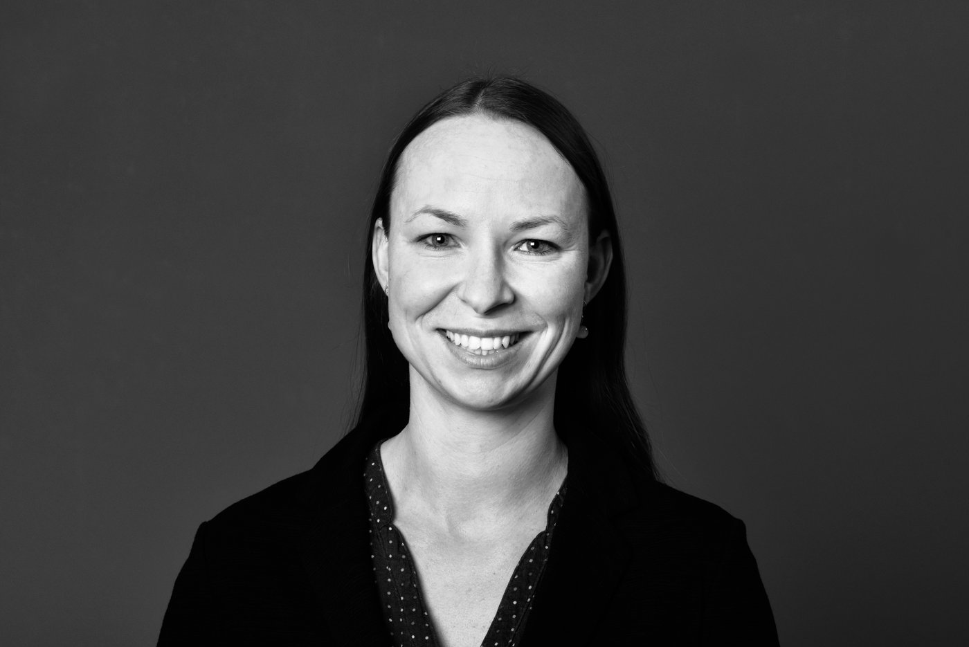 The black-and-white portrait shows a friendly smiling researcher.