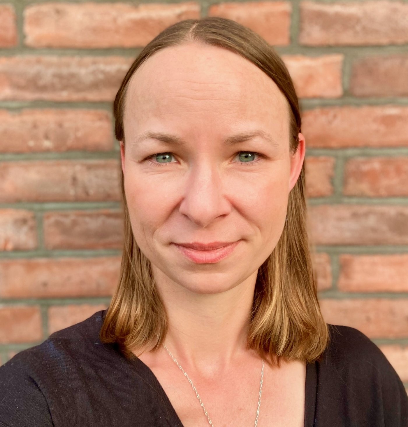 Dr. Maria Rosenthal, eine Forscherin mit mittellangen Haaren, einem schwarzen T-Shrit und Kette. Sie sieht freundlich in die Kamera.