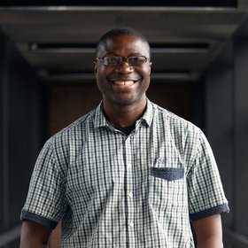 Dr Ayodeji Olayemi: A researcher who wears short black hair, glasses, a short grey-black beard and a check shirt.