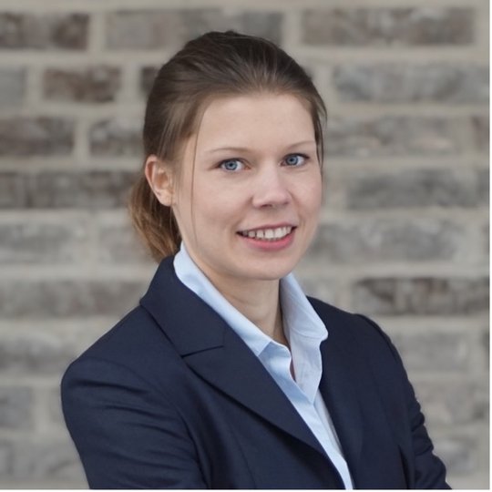 Dr. Michaela Raacke Porträtfoto von Michaela Raacke, einer Forscherin mit zurückgebundenen Haaren, hellem Hemd und dunklem Blazer und offenem Lächeln