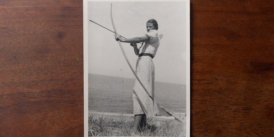 A black and white picture of a person shooting with a bow