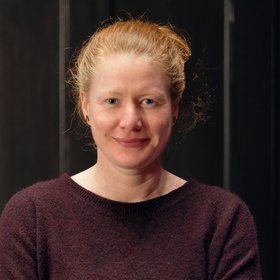 PhD Kathrin Schuldt: a researcher with blonde-reddish hair tied into a braid and a burgundy top.