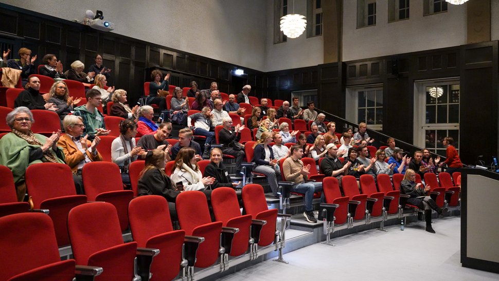 Das Foto zeigt den historischen Hörsaal des BNITM. Auf den roten Stühlen sitzen Besucher:innen.