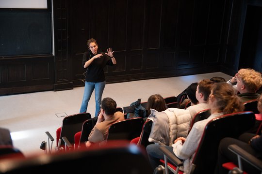 Das Foto zeigt die Forscherin Dr. Nicole Gilberger im Hörsaal des BNITM vor der Tafel vorm Publikum stehen und gestikulieren.