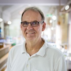 Dr Jörg Blessmann: a doctor in a white polo shirt, wearing glasses and short gray hair.