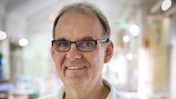 Dr. Jörg Blessmann: ein Arzt in weißem Poloshirt, der eine Brille und kurzes graues Haar trägt.