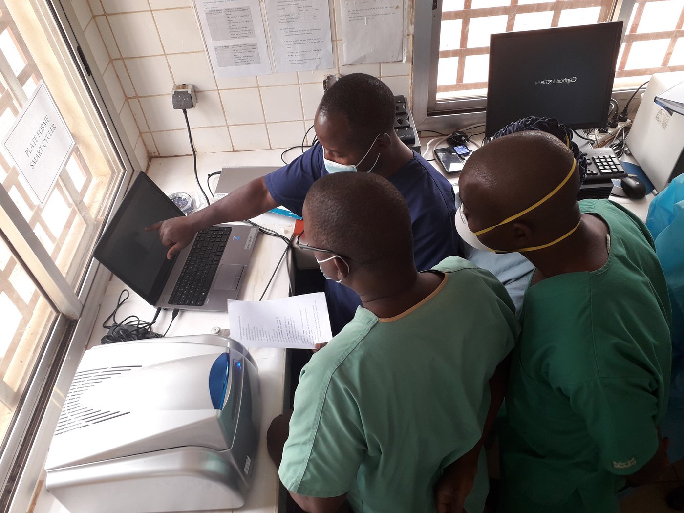 Das Bild zeigt drei afrikanische Forschende in einer Laborsituationvor einem Computer