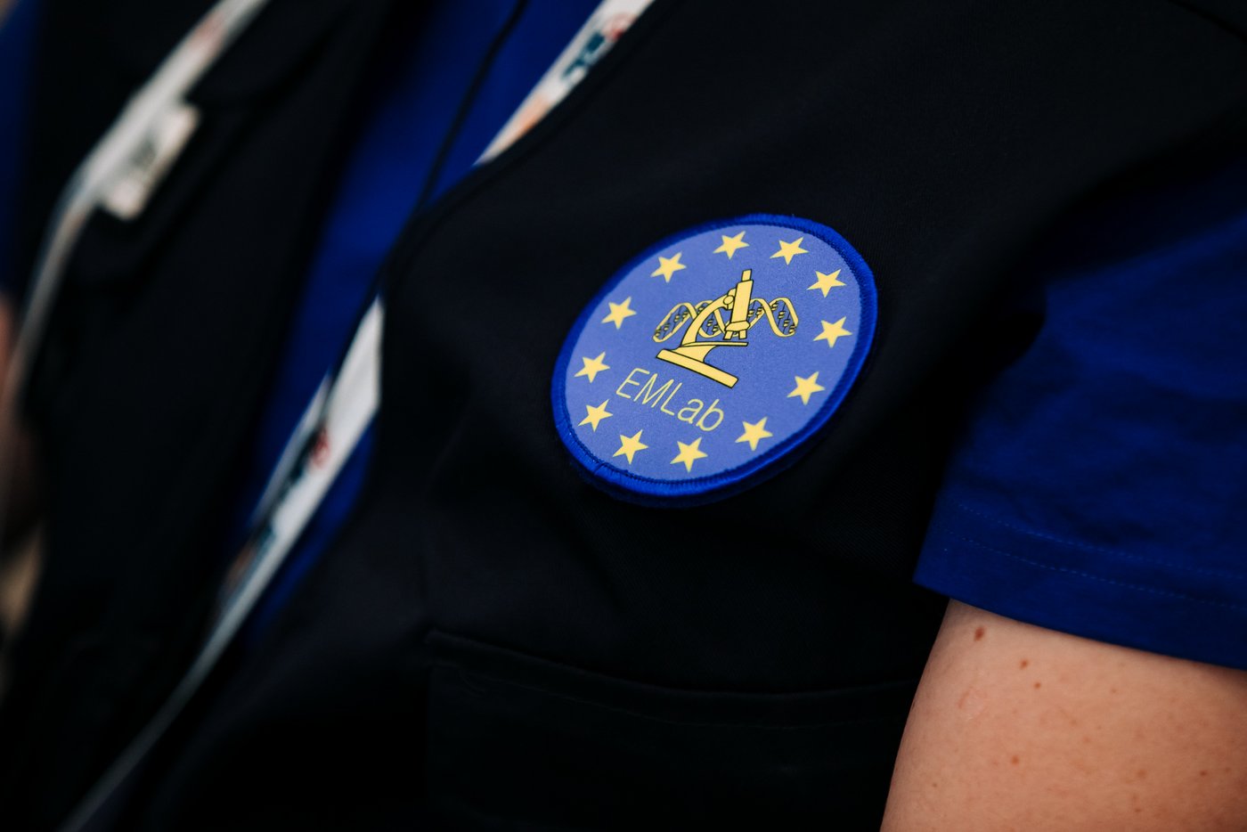 An EMLab expert wears his vest during a deployment. Close up of a man’s torso wearing blue EMLab branded vest and t-shirt