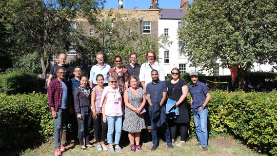 Die internationalen Mitglieder des tropEd-Netzwerks für "Education in International Health" stehen lächelnd in einem Garten.