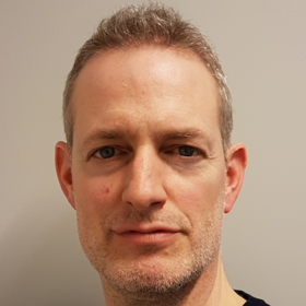 Dr Tobias Spielmann: a researcher with short, grey hair and a three-day beard, wearing a dark top.