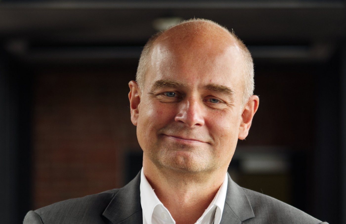 Prof. Dr Jürgen May: a researcher who is bald and wears a white shirt with a grey jacket.