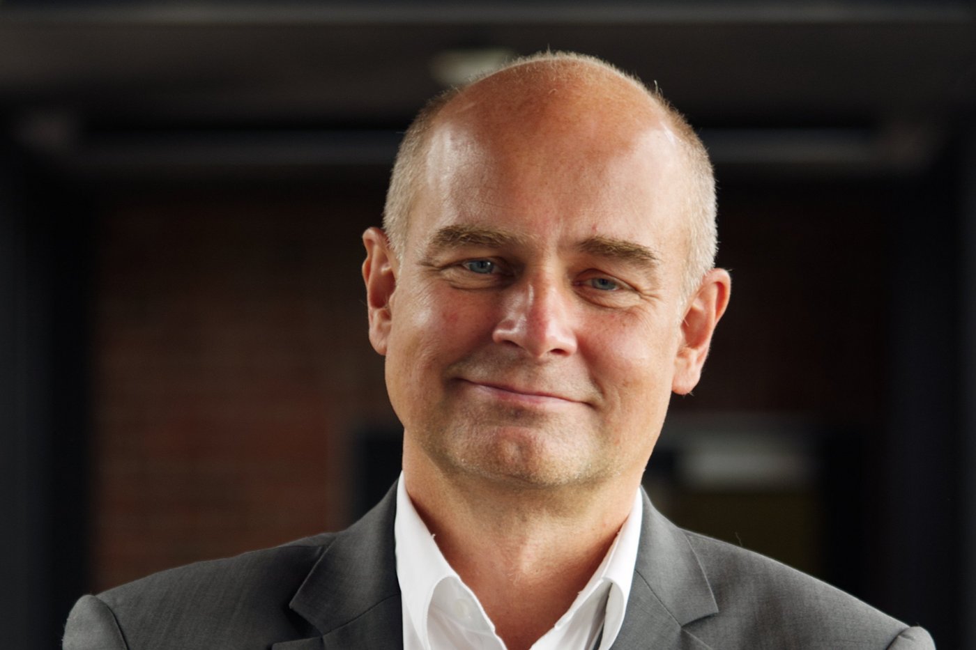 Prof. Dr Jürgen May: a researcher who is bald and wears a white shirt with a grey jacket.