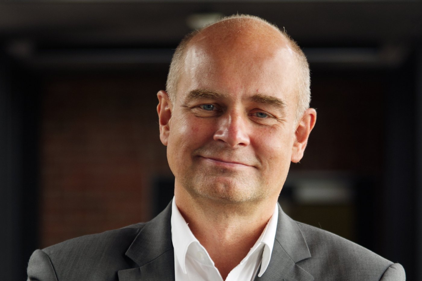 Prof. Dr. Jürgen May:a researcher who is bald and wears a white shirt with a gray jacket.