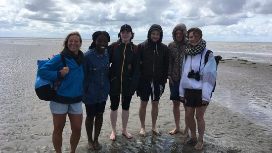 AG Helminthen-Immunologie im Watt bei Büsum. AG Helminthen-Immunologie im Watt bei Büsum: eine Gruppe von 6 Menschen stehen barfuß und mich hochgekrempelten Hosen im Watt und lachen in die Kamera. Im Hintergrund ist ein wolkiger Himmel zu sehen.