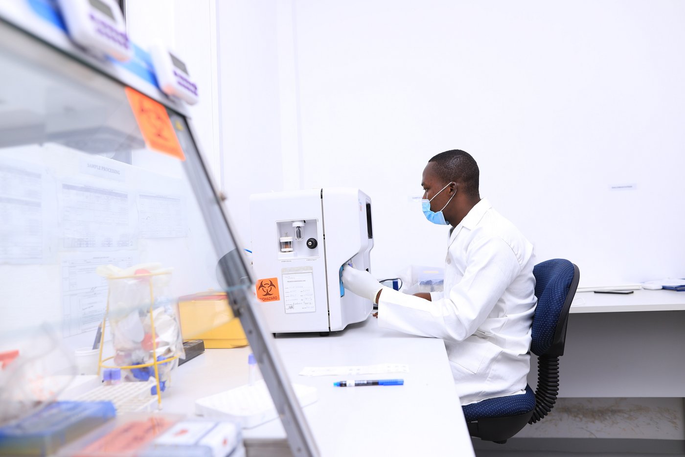 The photo shows a scientist at a technical device labelled "Bio Hazard". Next to it is a glovebox.