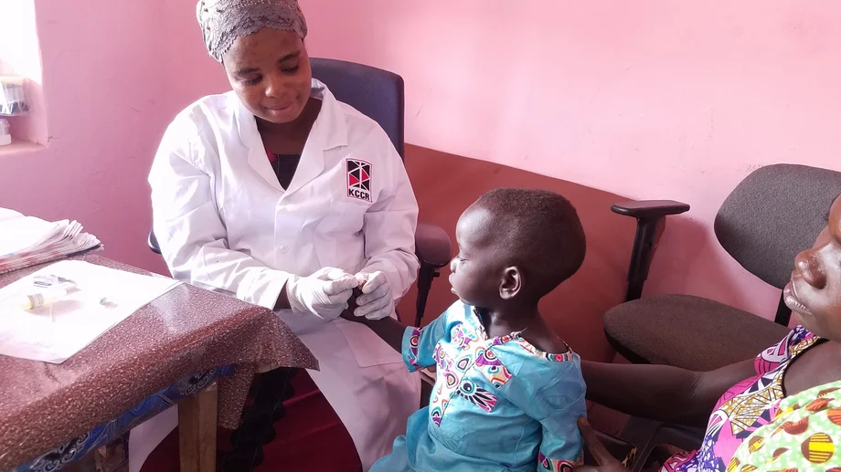 Eine KCCR-Mitarbeiterin nimmt Blut an der Fingerkuppe eines Kleinkindes ab, um es auf Malaria zu testen.