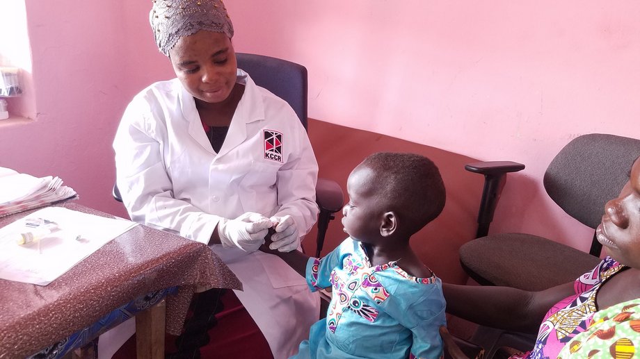 Eine KCCR-Mitarbeiterin nimmt Blut an der Fingerkuppe eines Kleinkindes ab, um es auf Malaria zu testen.