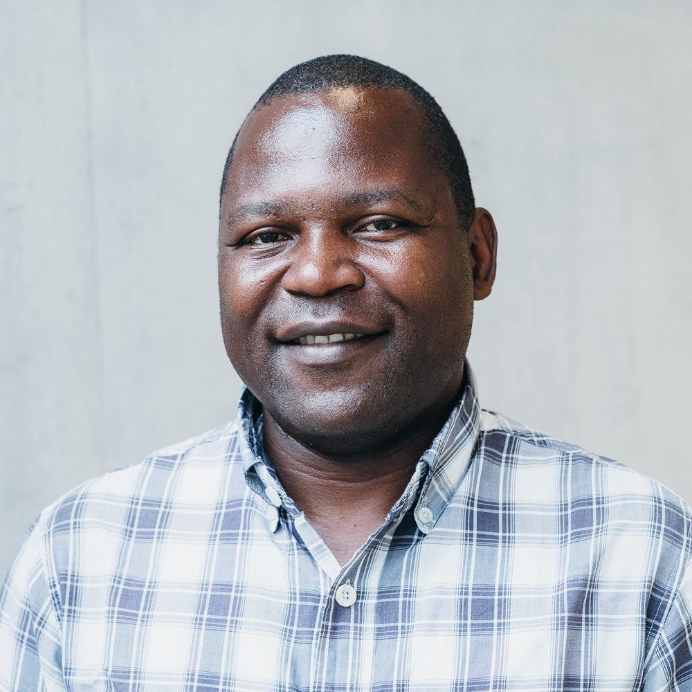 Portrait of a male black person wearing a white and blue chequered shirt.
