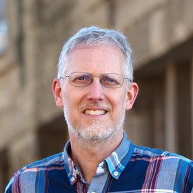 Dr. Stefan Berg: Ein Forscher, der kurzes, graues Haar, eine Brille und ein blau-rot kariertes Hemd trägt.