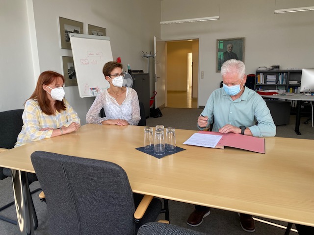 The picture shows three people signing the Diversity Charter.