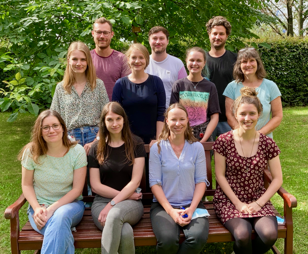 The picture shows a group of researchers placed around a garden bench.