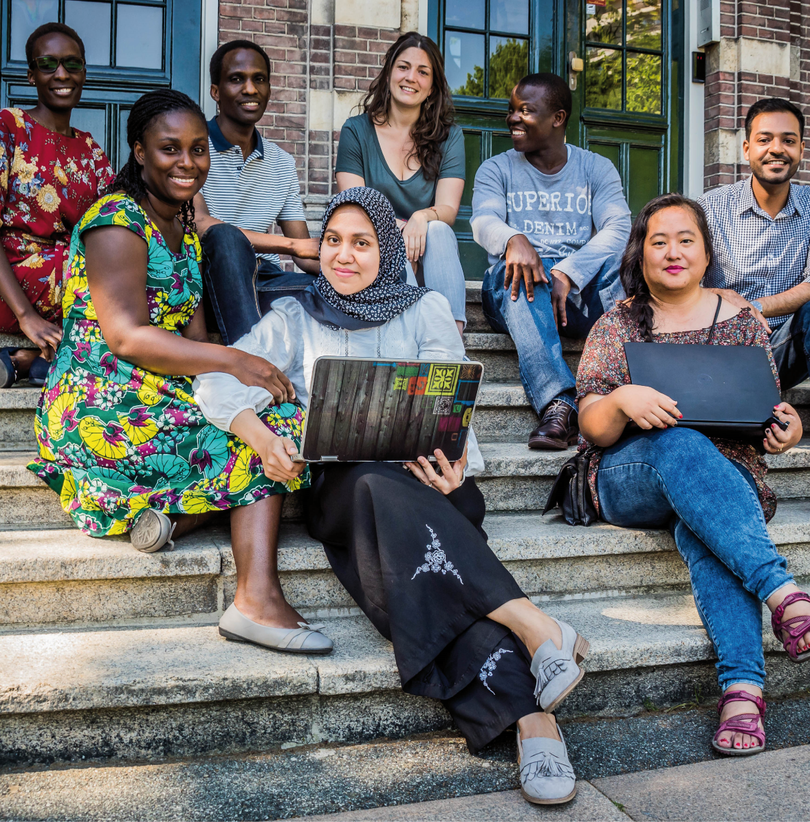The picture shows a group of international diverse students sitting outside on a staircase